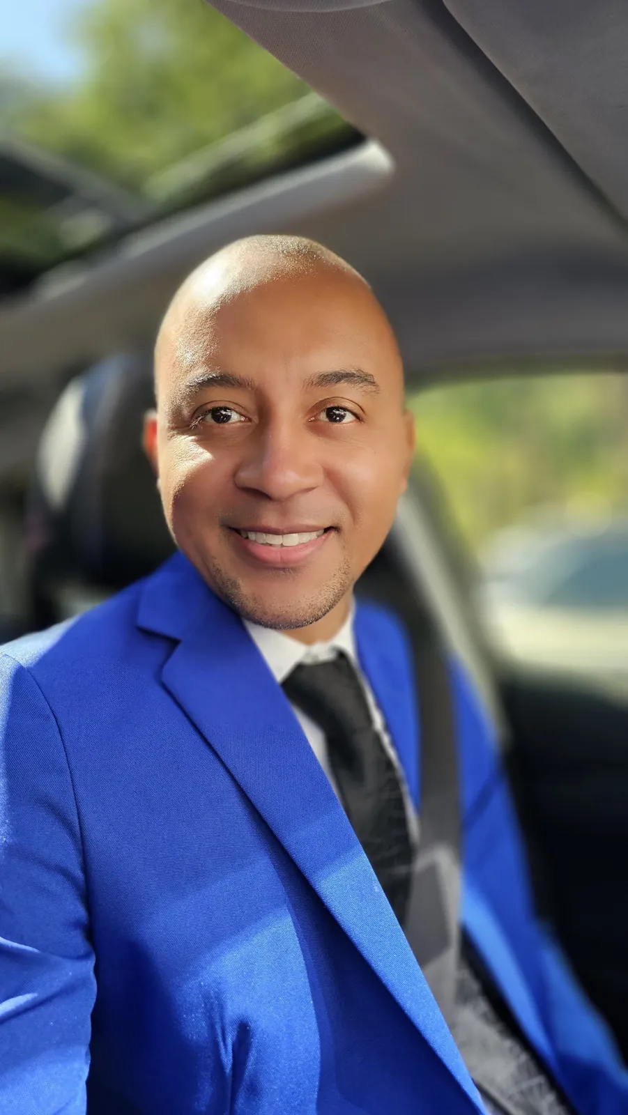 Bruno Inácio, motorista executivo de terno azul e gravata, ao volante do carro do transfer Belvedere para Confins