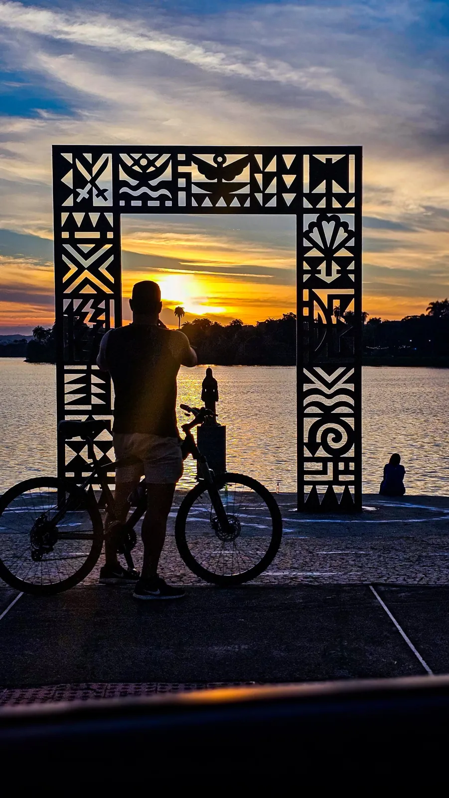 Pôr do sol na orla da Lagoa da Pampulha visto através de um portal decorado, em Belo Horizonte