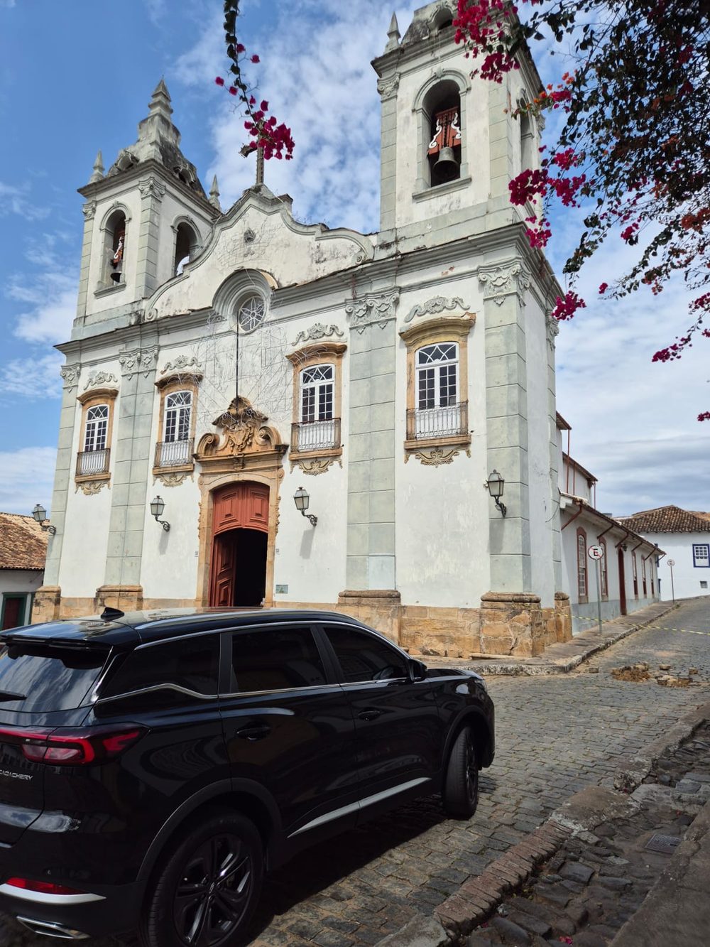 SUV executivo em rua de pedra diante de igreja histórica na região de Tiradentes e São João del-Rei