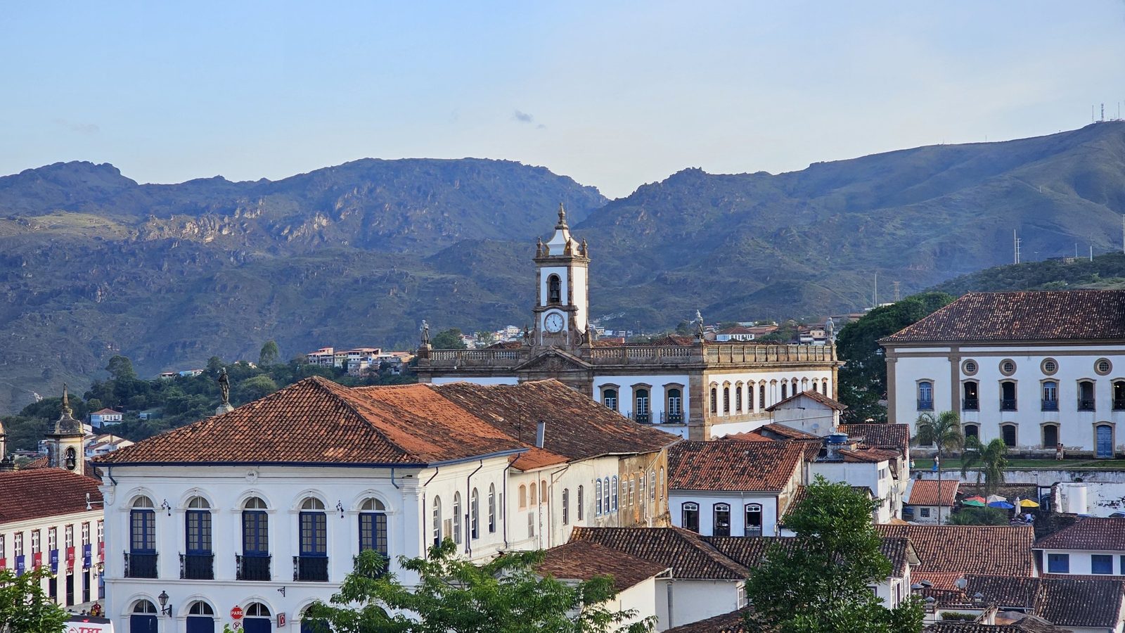 Casarões e torre do relógio de Ouro Preto com as montanhas da serra ao fundo